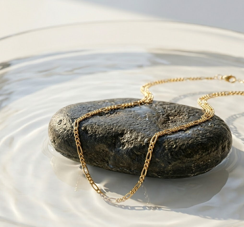 Gold necklace draped over a stone in water