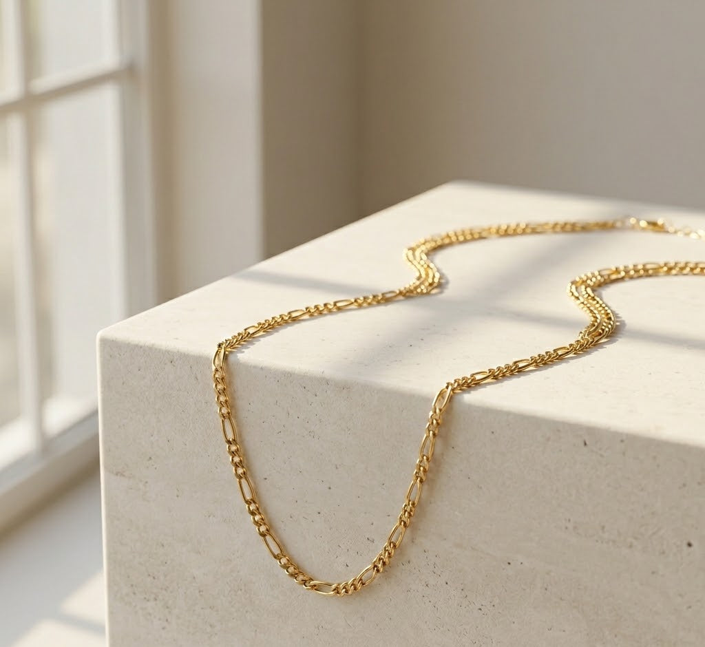 Gold chain necklace on a light stone surface with a soft background